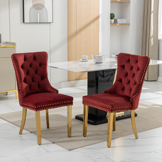 Two plush red velvet dining chairs with gold accents and tufted backs