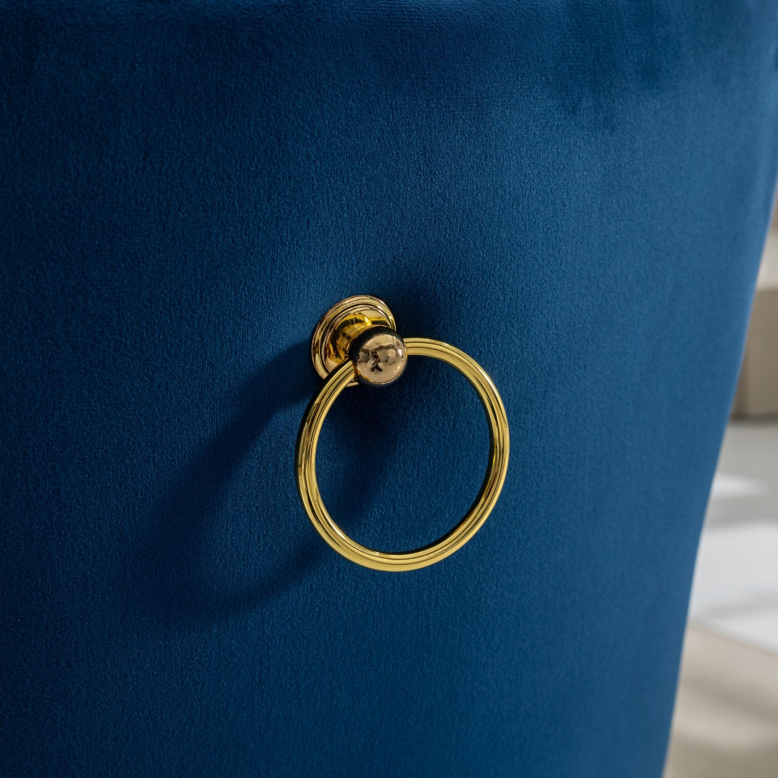 Closeup of navy blue velvet chair back with gold ring pull
