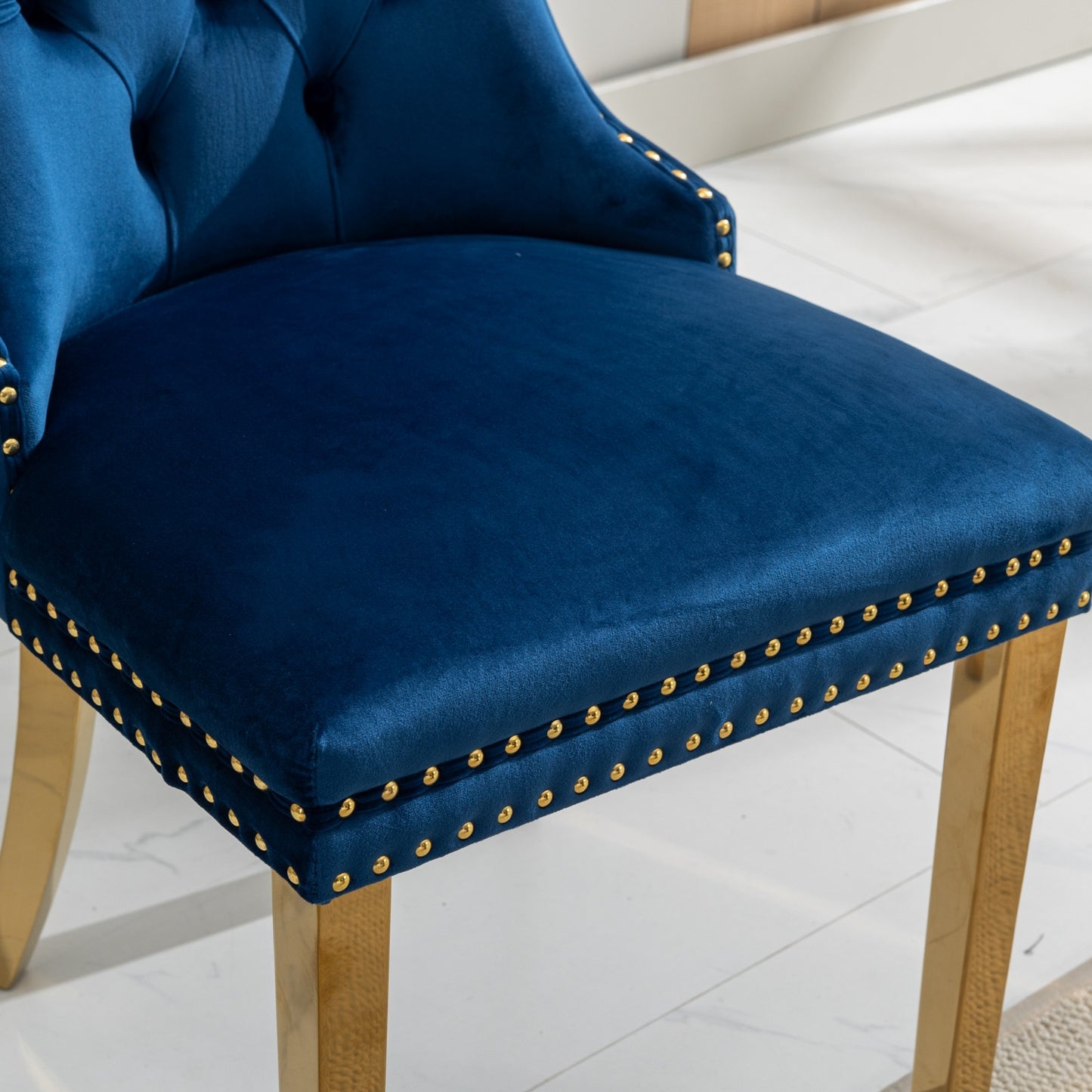 Deep blue velvet accent chair with tufted back and gold nailhead trim
