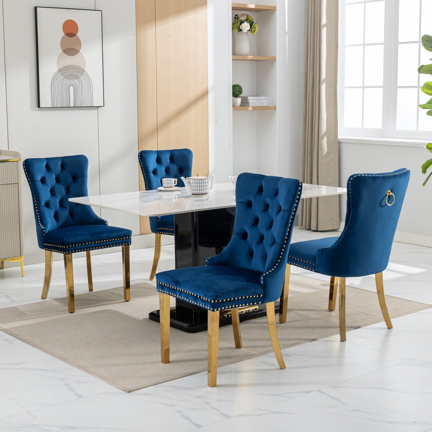 Four blue velvet dining chairs with gold trim and legs arranged around a marble table