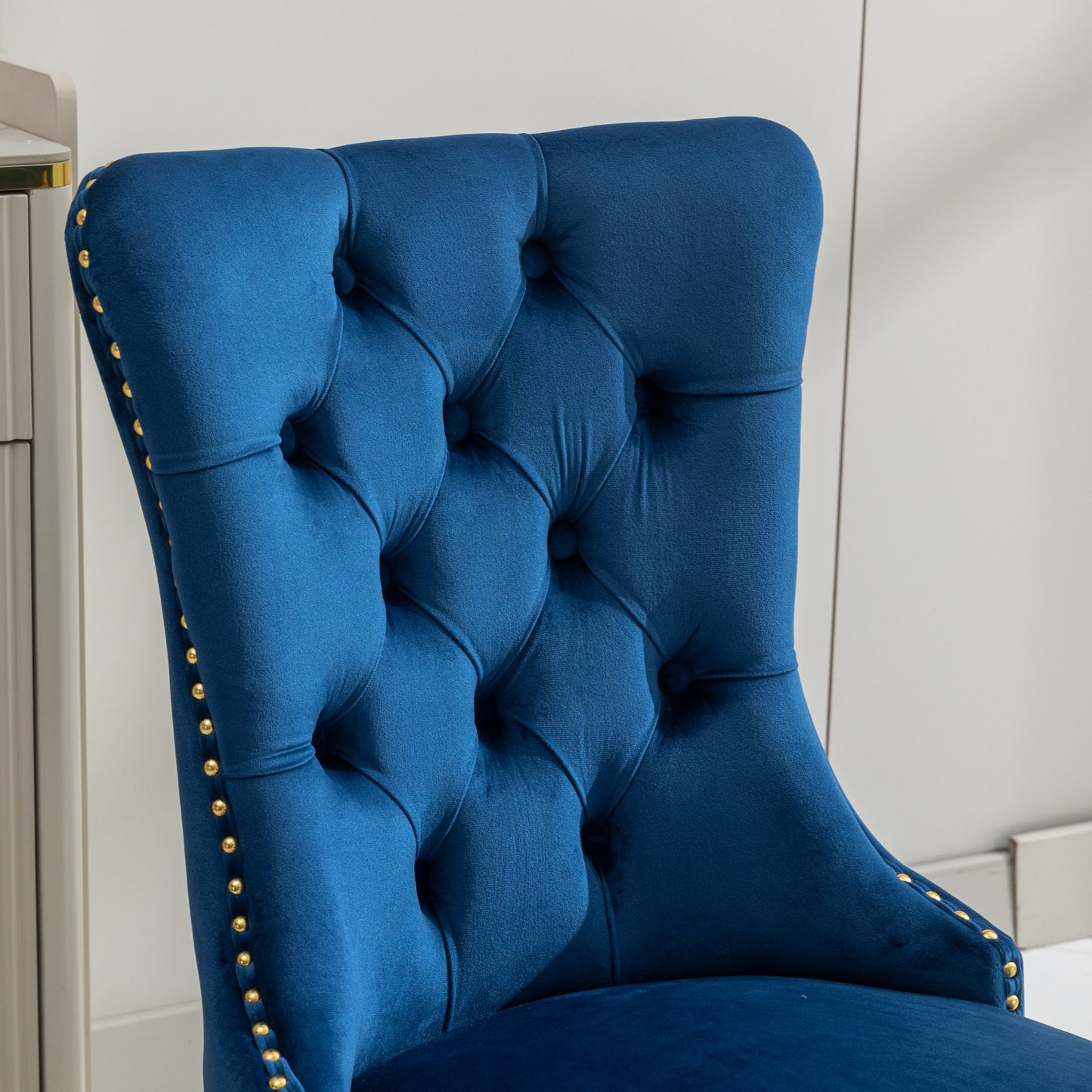 Deep blue velvet dining chair with diamond tufting and brass nailhead trim
