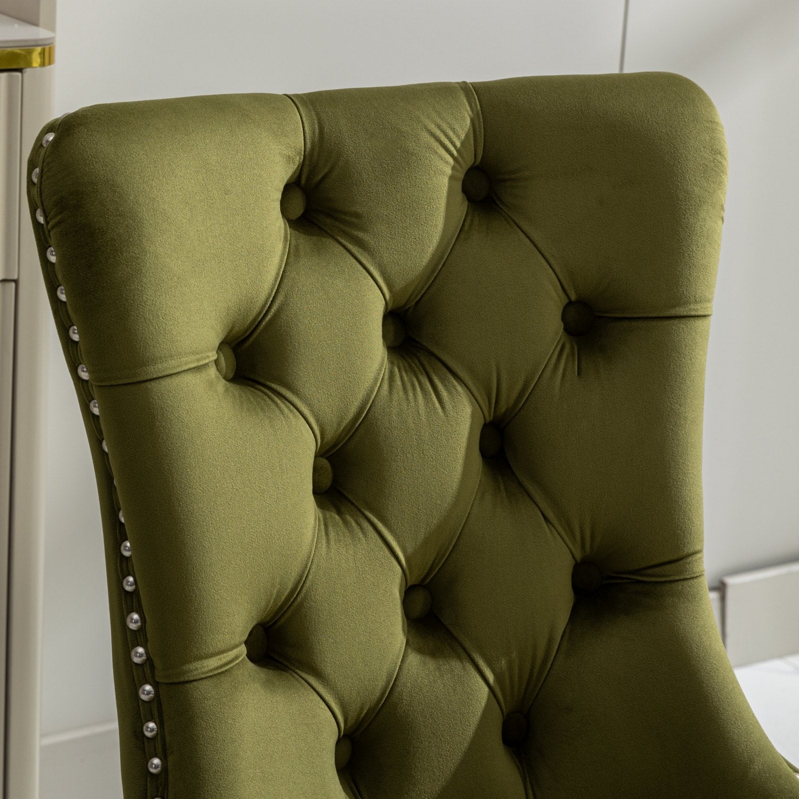 Olive green velvet dining chair with button tufting and silver nailhead trim