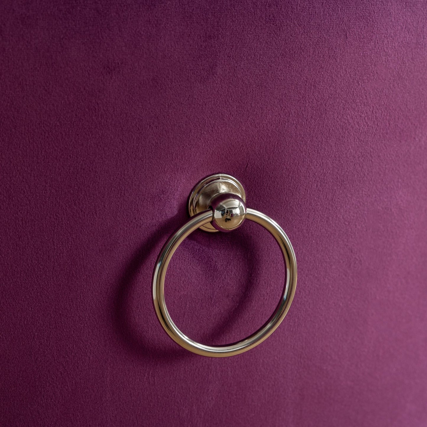 Closeup of a silver ring pull on a deep purple velvet ottoman