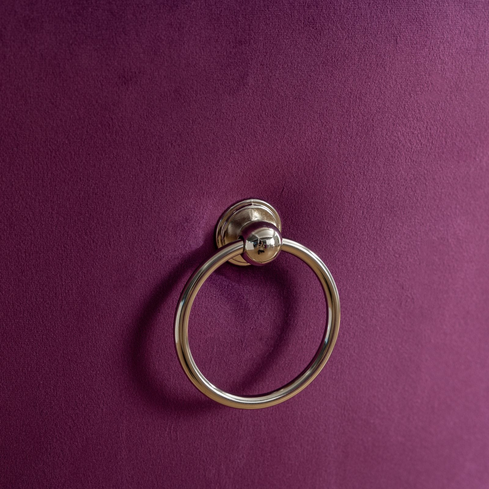 Closeup of a silver ring pull on a deep purple velvet ottoman