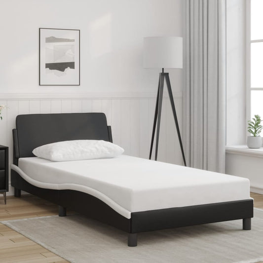 Black leatherette single bed frame with white mattress and pillow