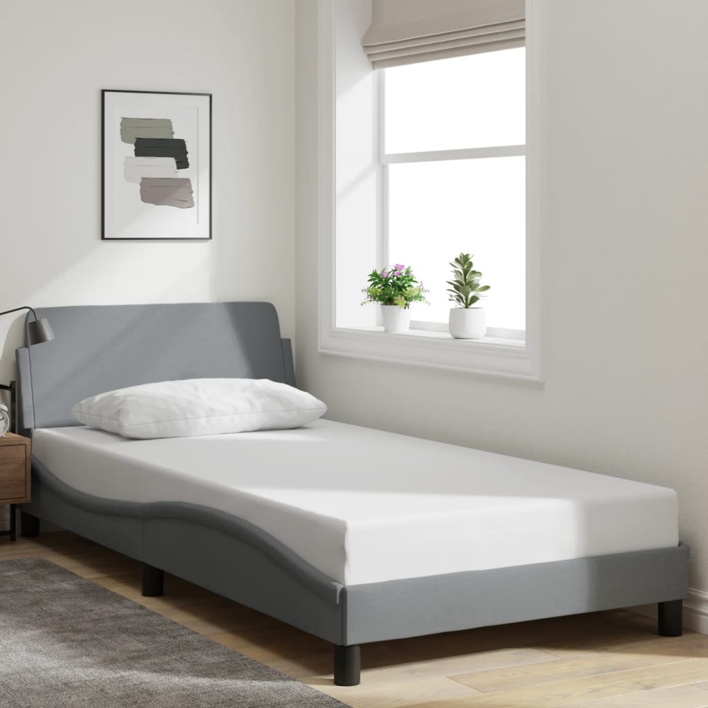 Grey upholstered twin bed frame with white mattress and pillow