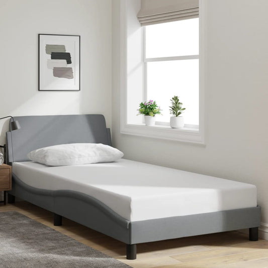 Grey upholstered twin bed frame with white mattress and pillow
