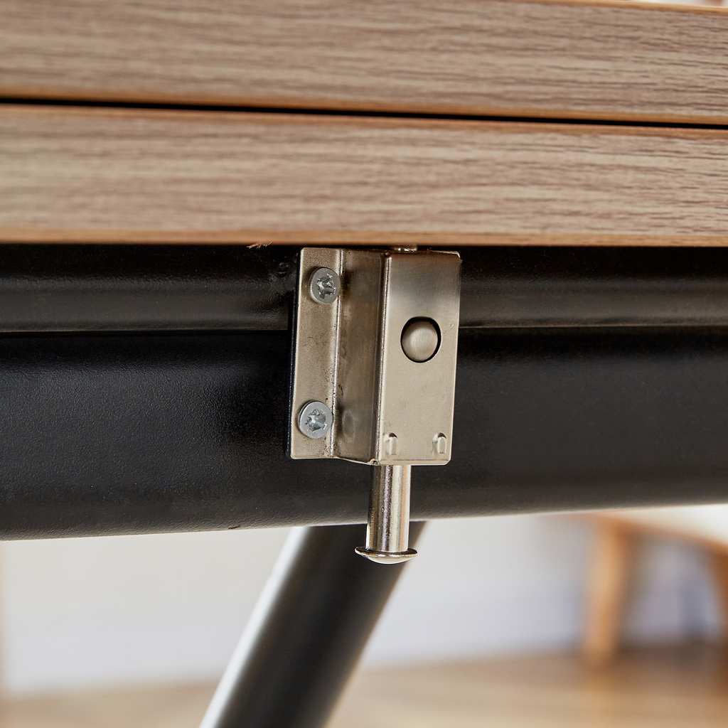 Closeup of a metal latch mechanism on a black frame with a wooden tabletop