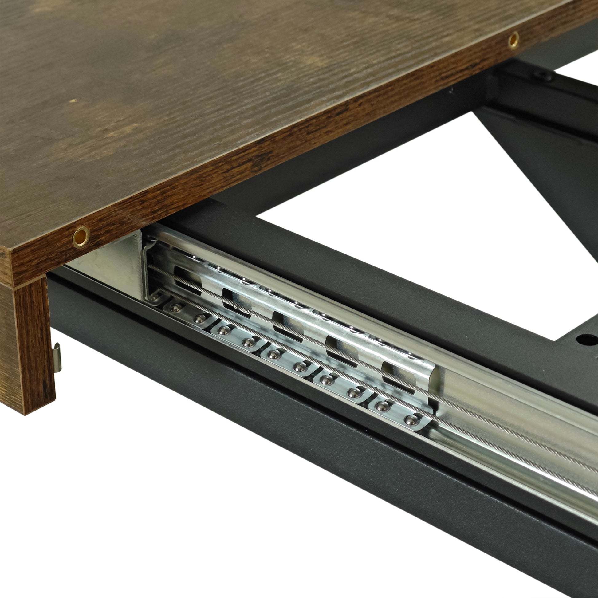 Dark wood table edge showing metal drawer slides and steel cables for extension