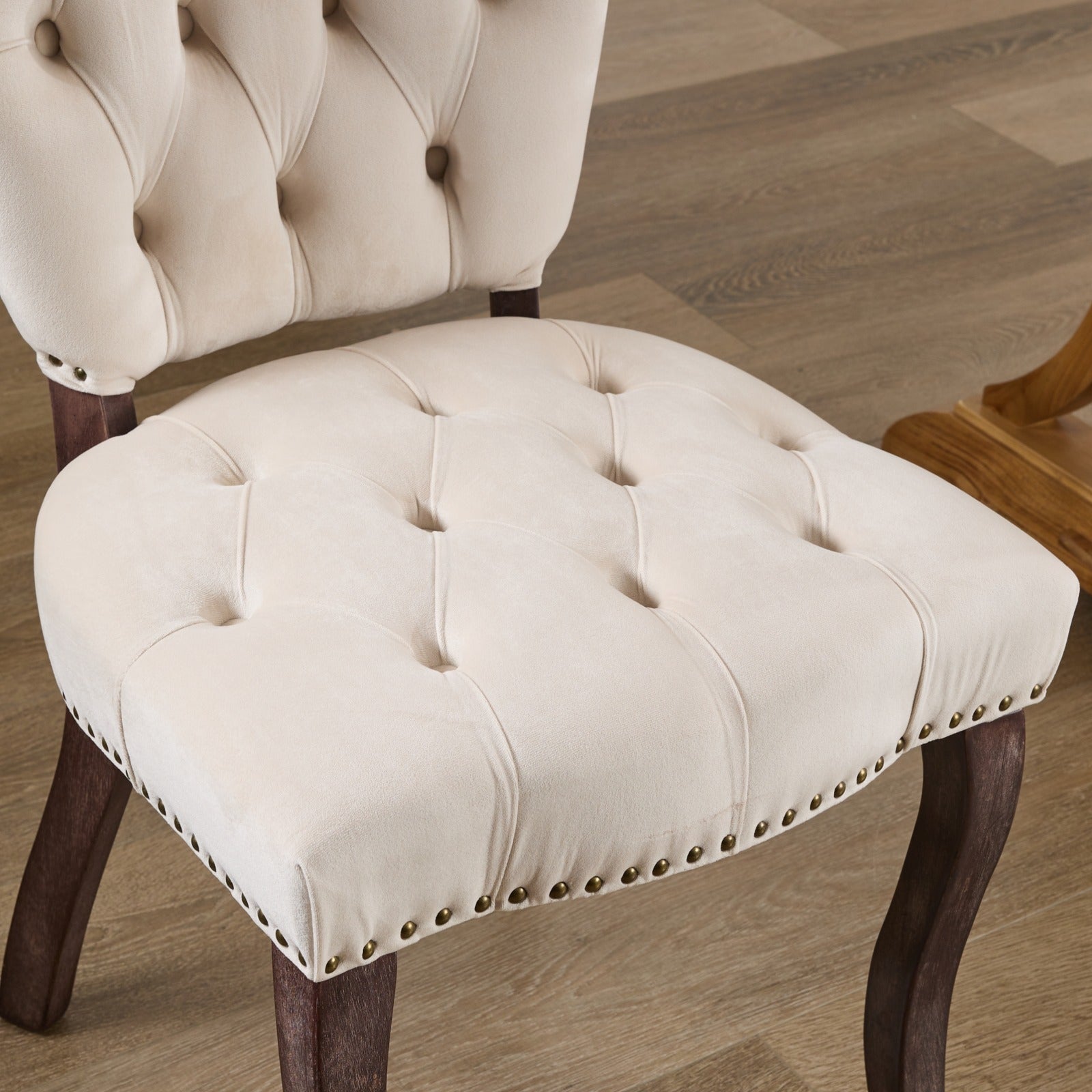 Cream velvet accent chair with button tufting and brass nailhead trim