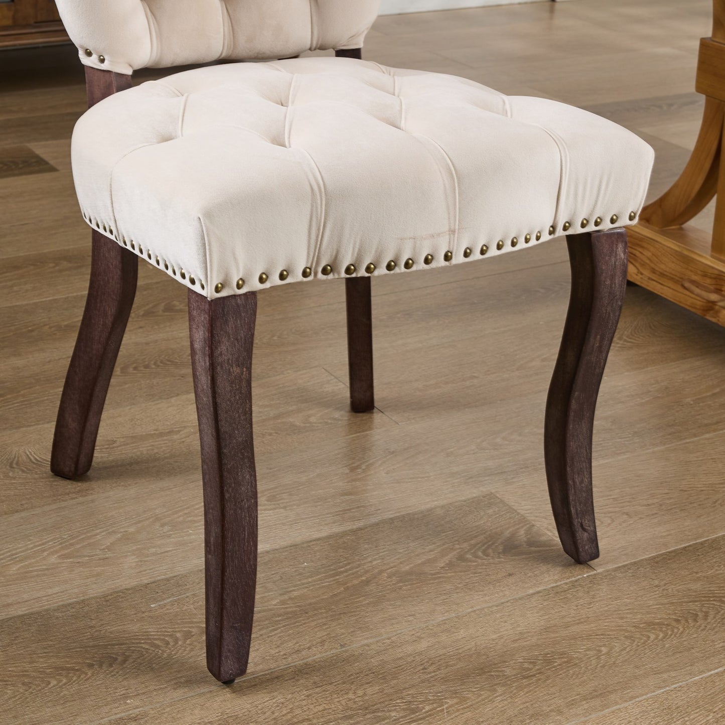 Cream velvet upholstered dining chair with tufted seat and dark wood legs