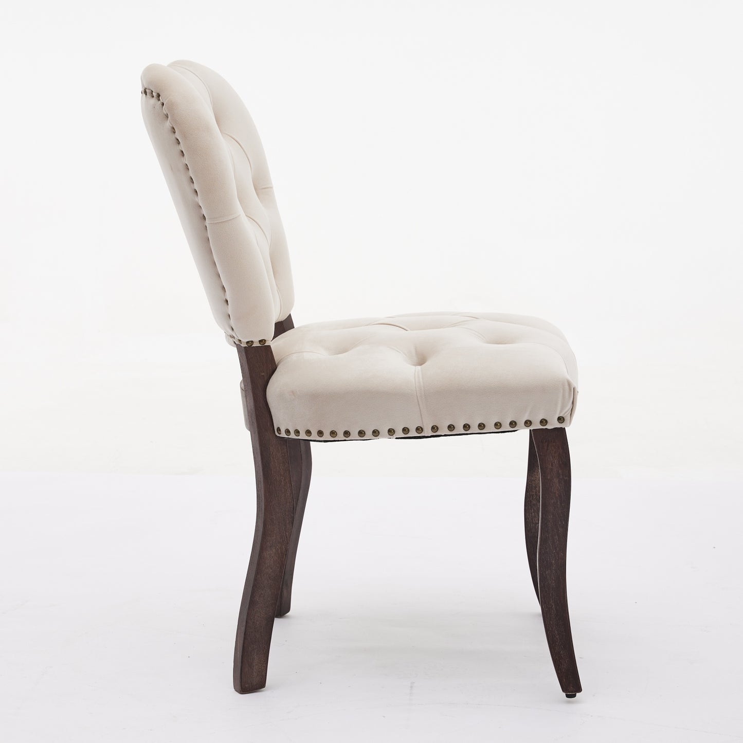 Tufted cream velvet dining chair with dark wood legs and brass nailhead trim