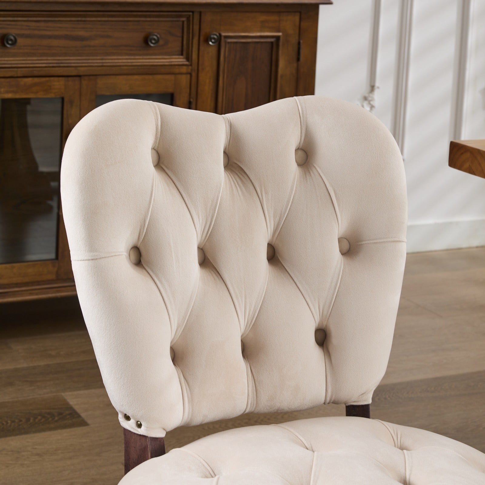 Cream velvet dining chair with tufted back and brass nailhead trim