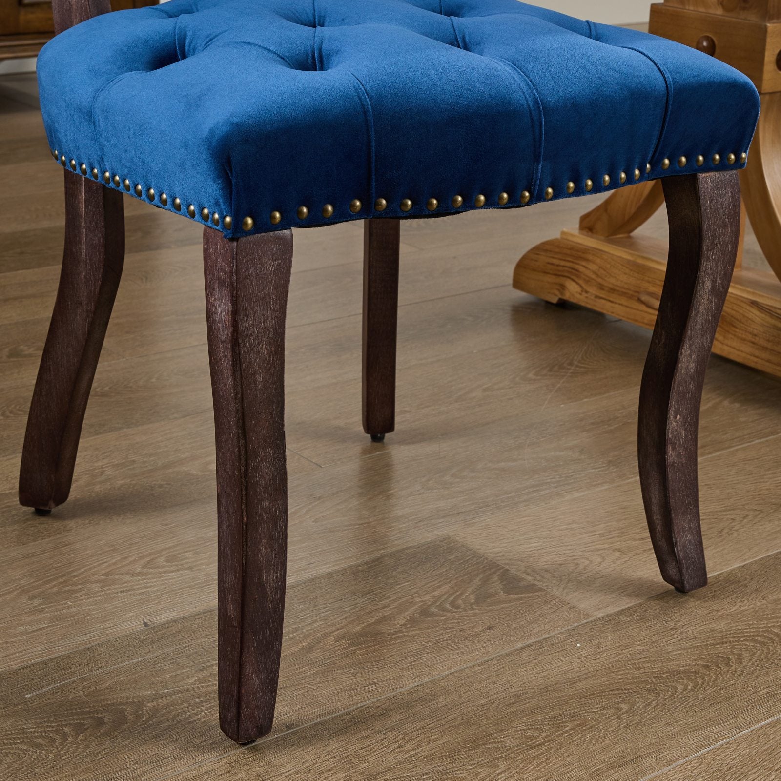 Deep blue velvet dining chair with tufted seat and brass nailhead trim