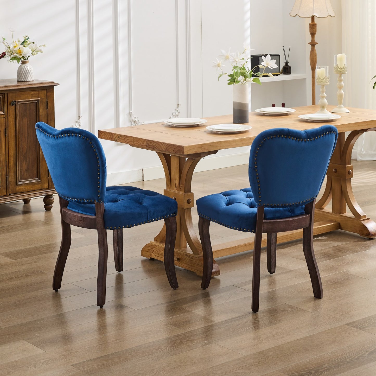 Tufted royal blue velvet dining chair with antique brass nailhead trim and dark wood legs
