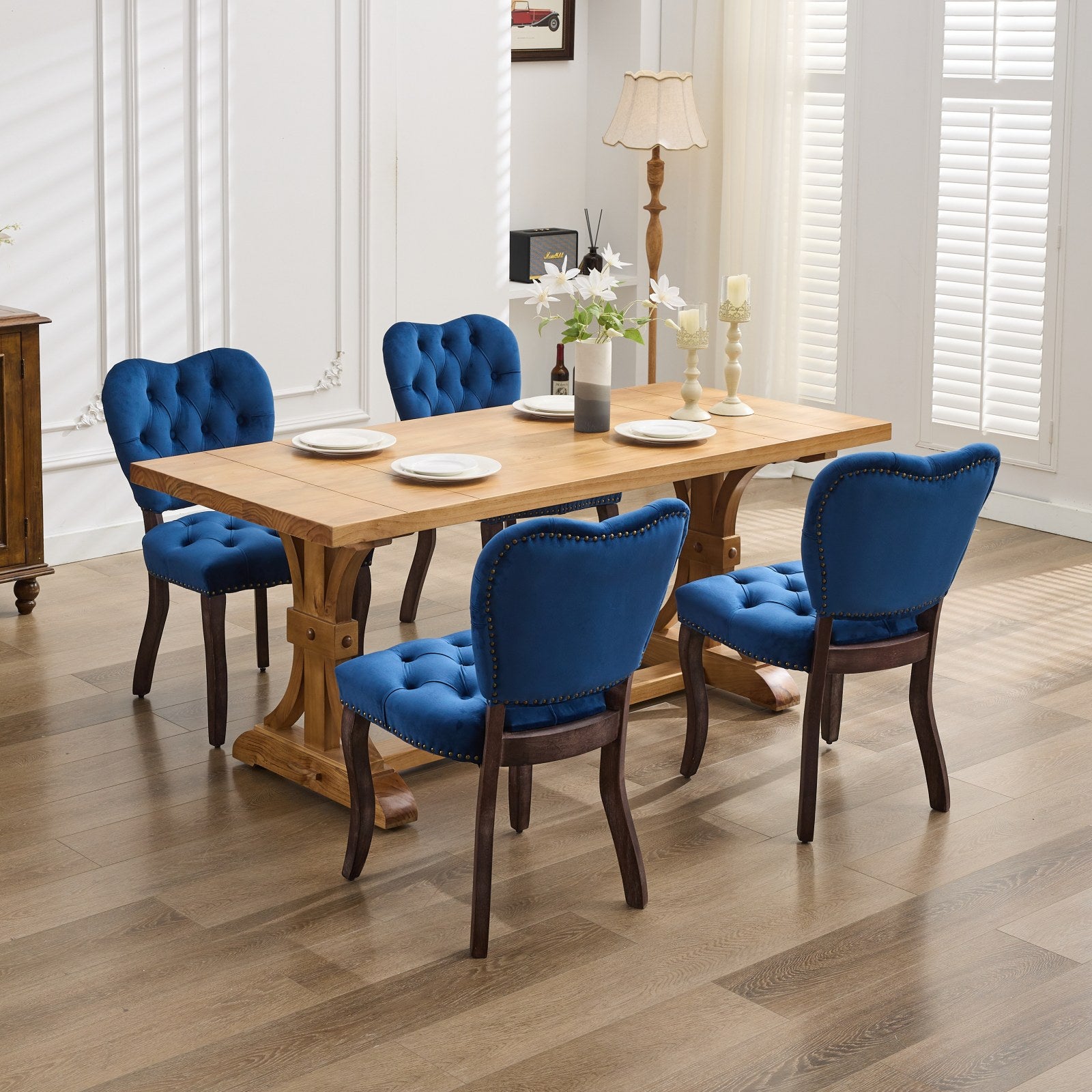 Tufted navy blue velvet dining chairs with nailhead trim around a solid oak table