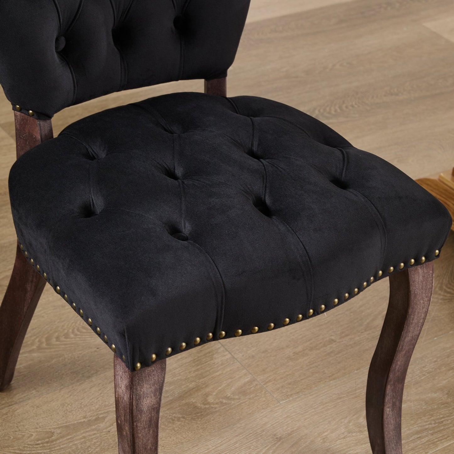 Black velvet dining chair with tufted seat and brass nailhead trim