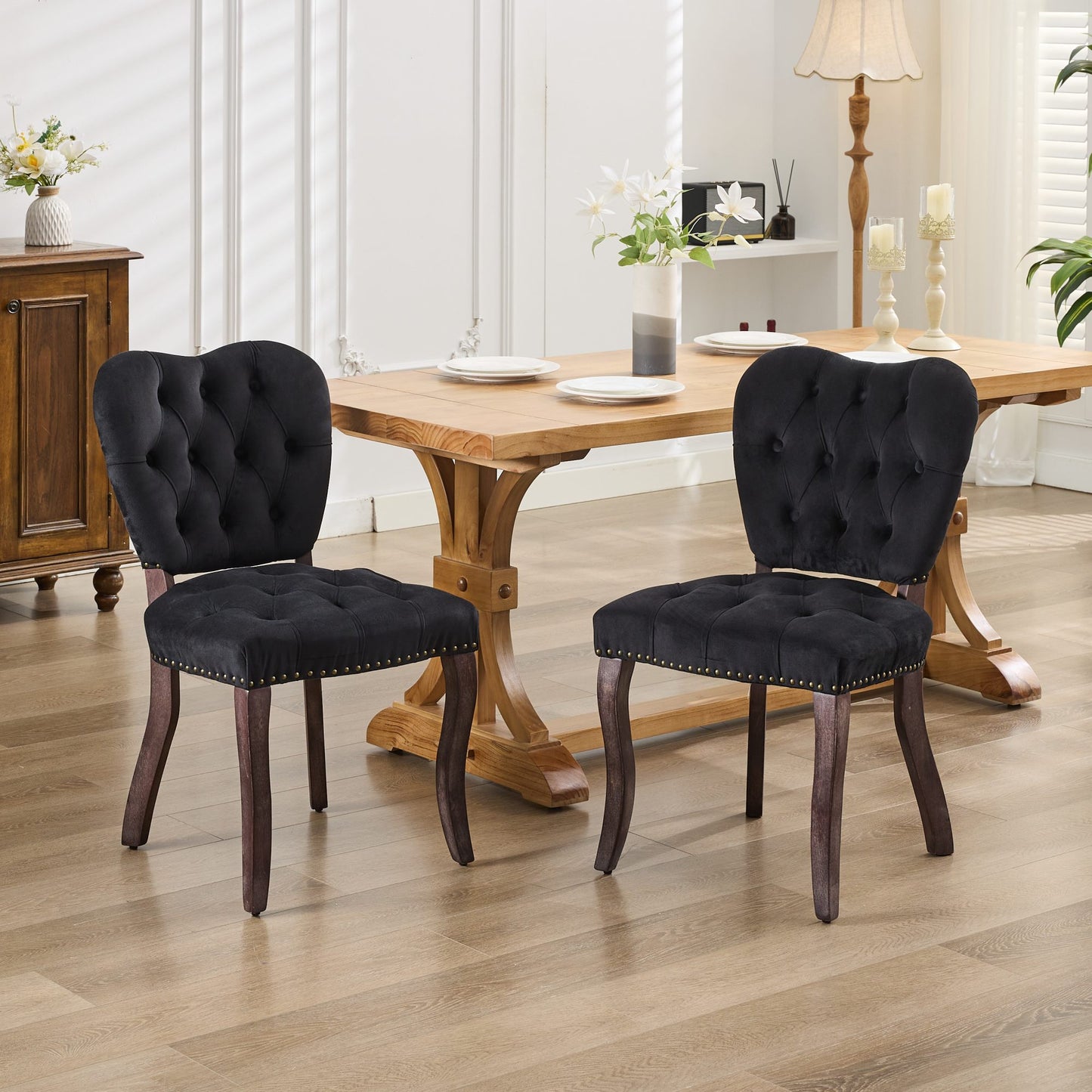 Black velvet dining chair with button tufting and brass nailhead trim