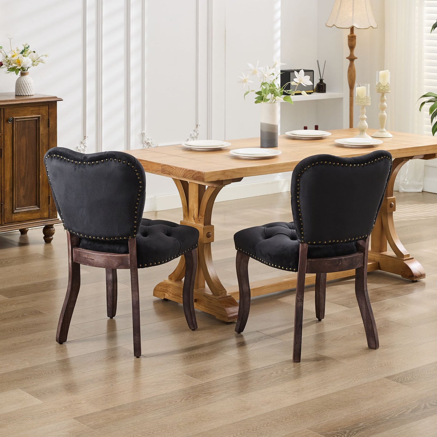 Black velvet dining chairs with nailhead trim around a wooden table