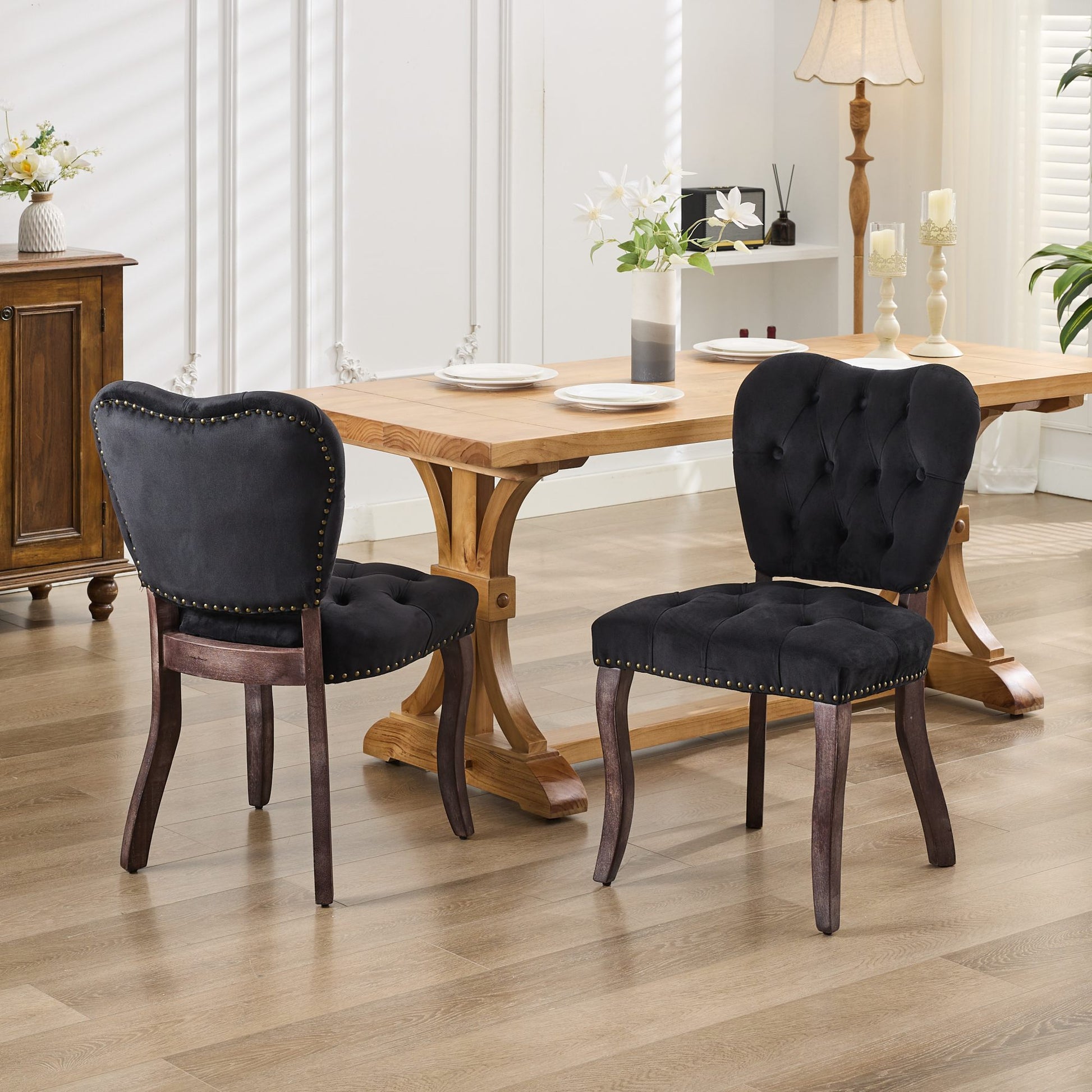 Black velvet dining chair with tufted back and brass nailhead trim