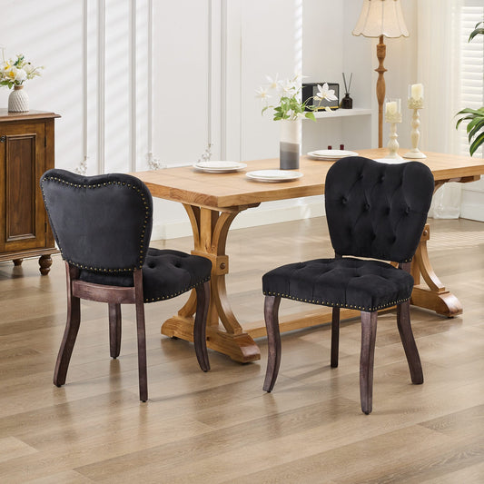 Black velvet dining chair with tufted back and brass nailhead trim