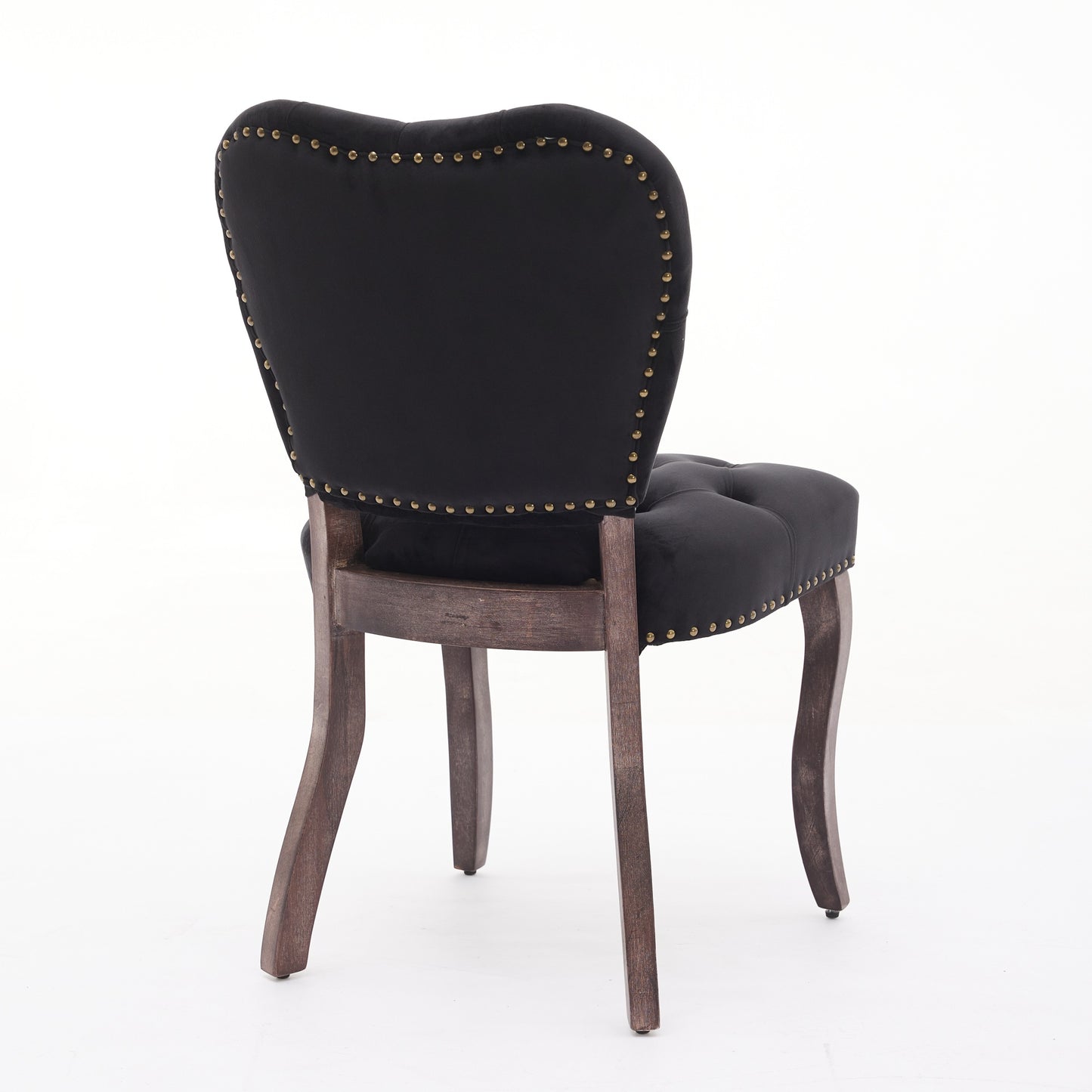 Black velvet tufted dining chair with brass nailhead trim and dark wood legs