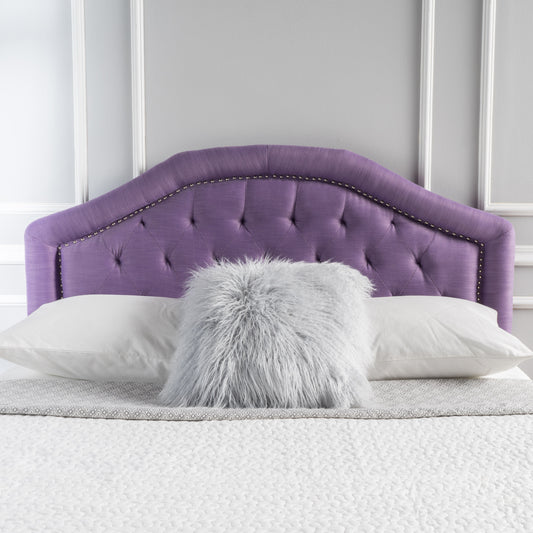 Tufted purple fabric headboard with nailhead trim on a bed with white pillows