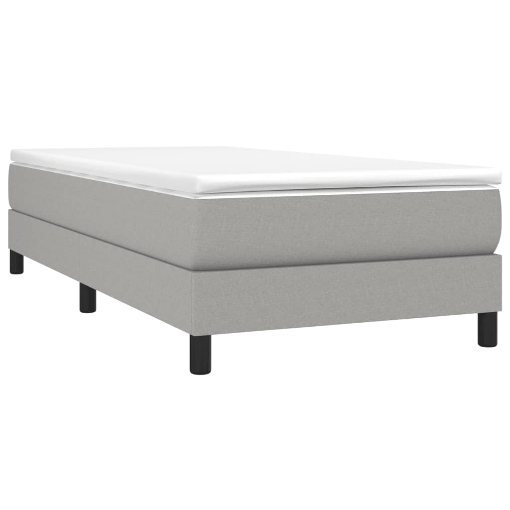 Gray upholstered divan bed with a white topper
