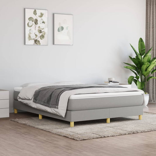 A contemporary grey upholstered divan bed with light wooden legs and a plush mattress