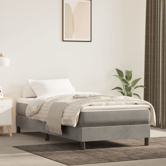 Grey upholstered single bed frame with a white mattress and bedding