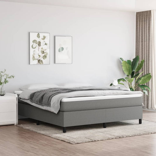 Grey upholstered bed frame with a thick mattress and a charcoal throw blanket