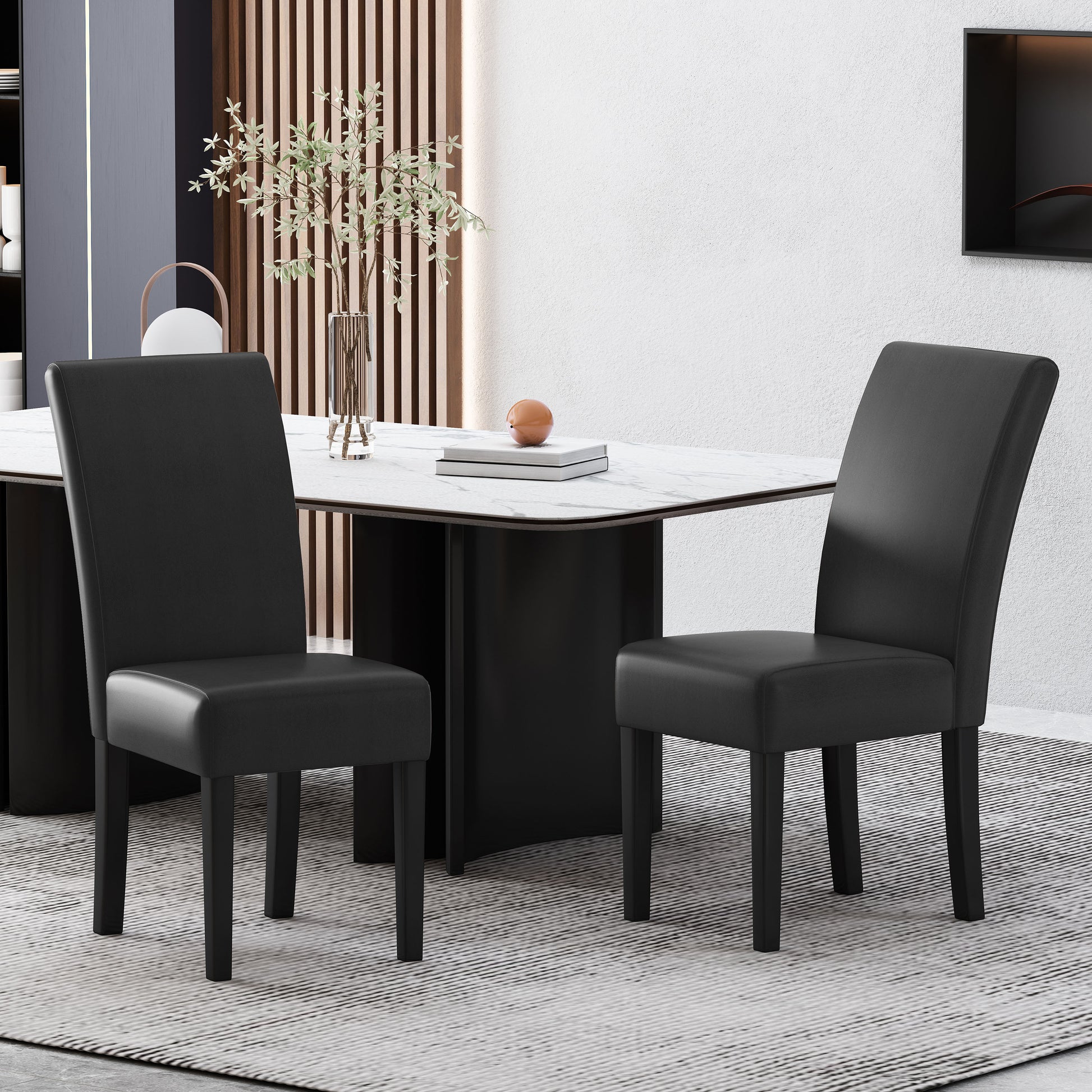 Two black faux leather dining chairs with slim black legs