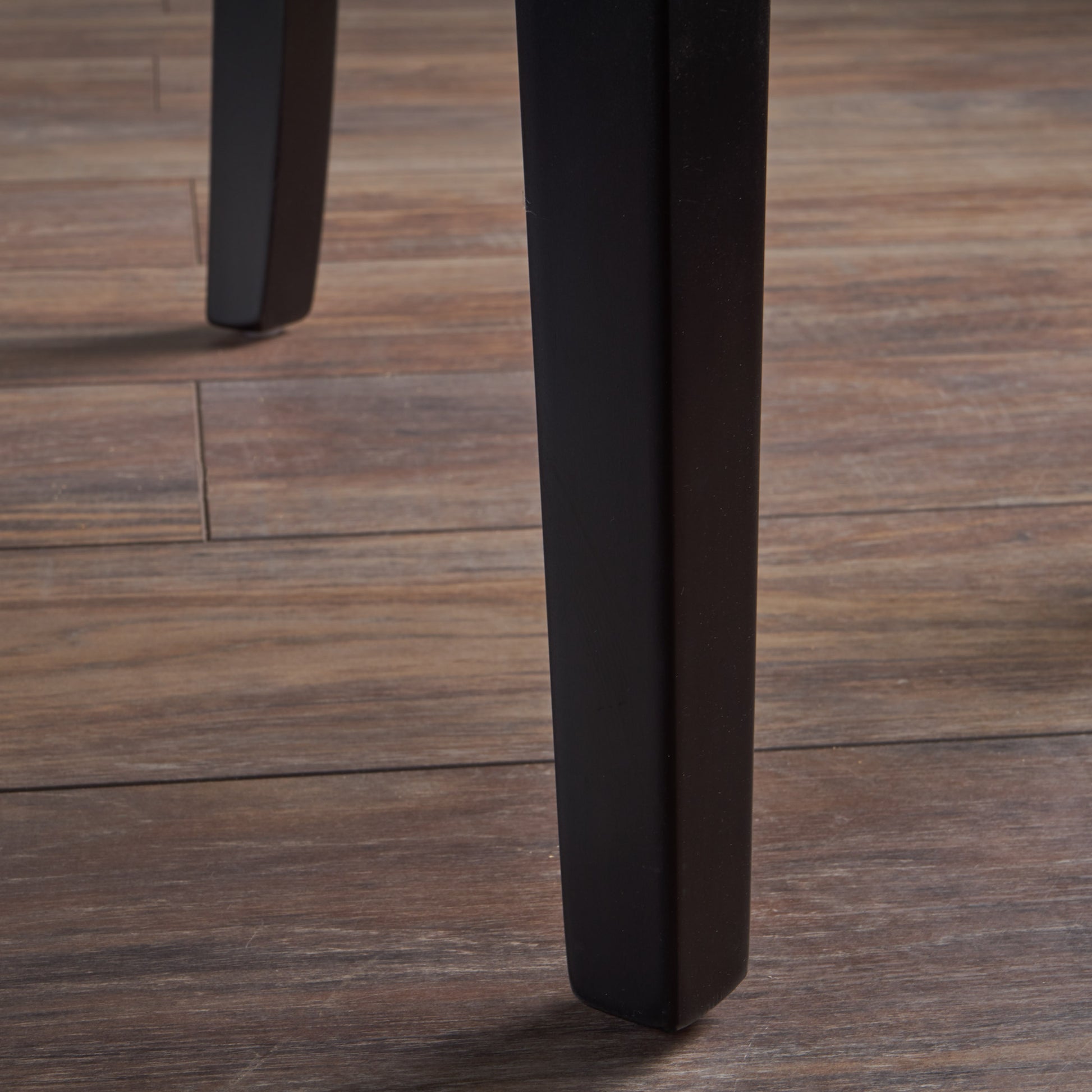 Black tapered table leg on distressed wood floor