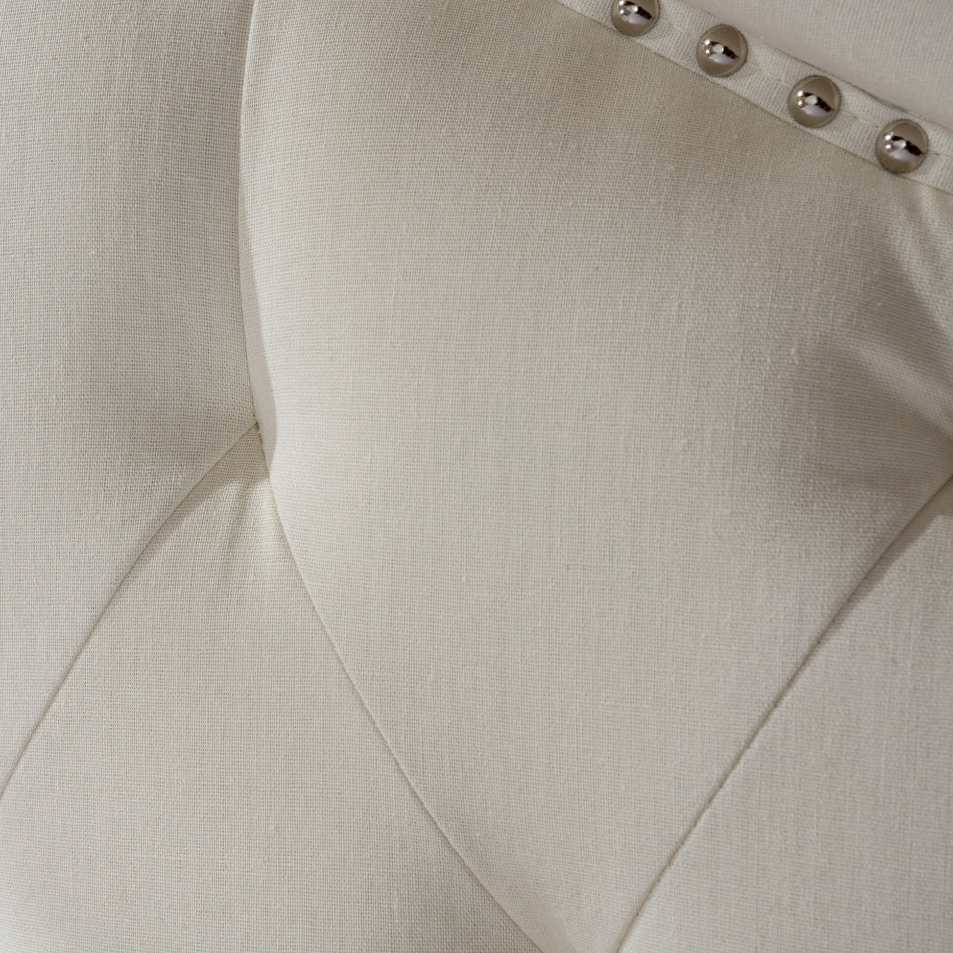 Tufted beige linen upholstery detail with silver nailhead trim