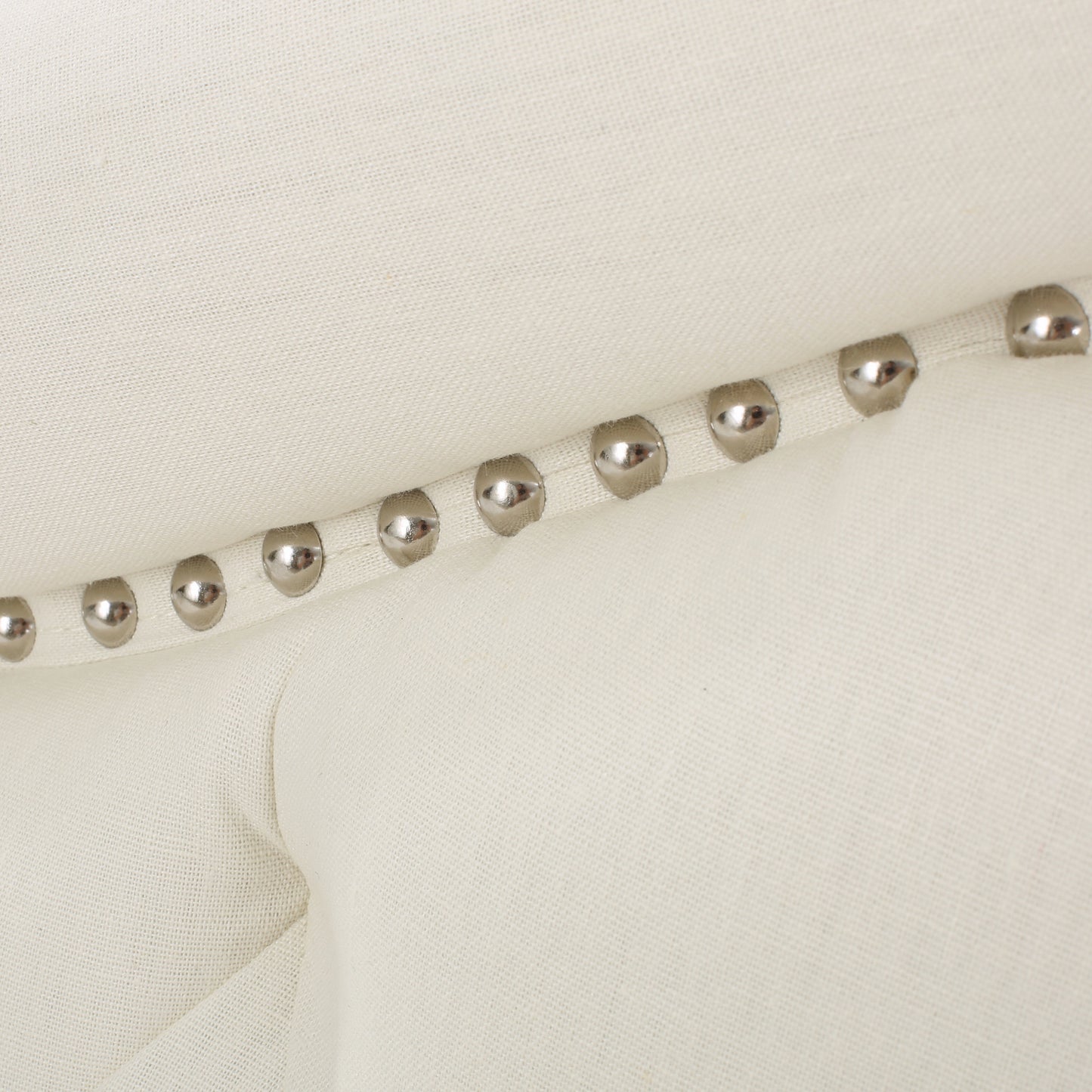 Cream linen tufted headboard detail with polished nailhead trim