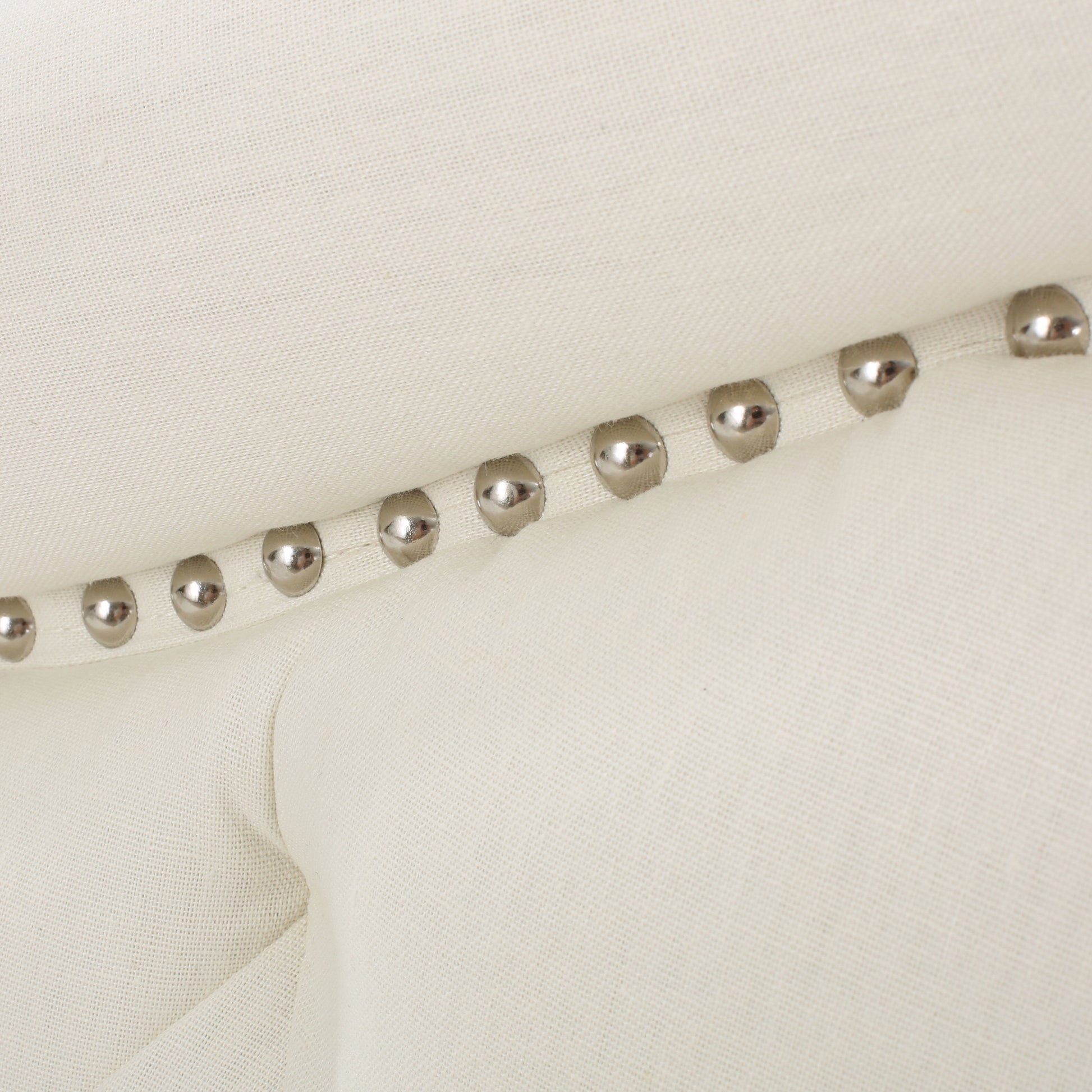 Cream linen tufted headboard detail with polished nailhead trim