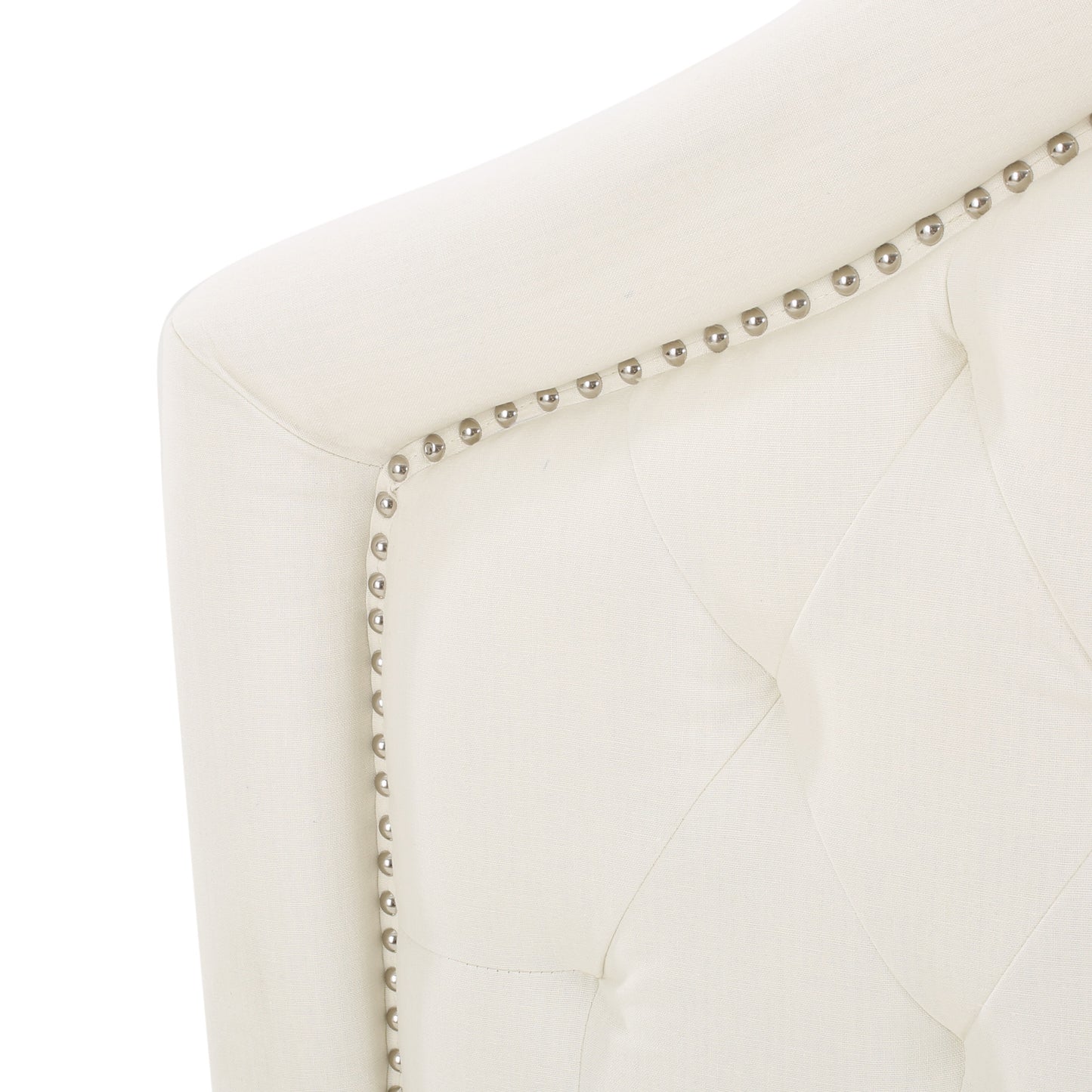 Cream upholstered armchair detail with tufted design and polished nailhead trim