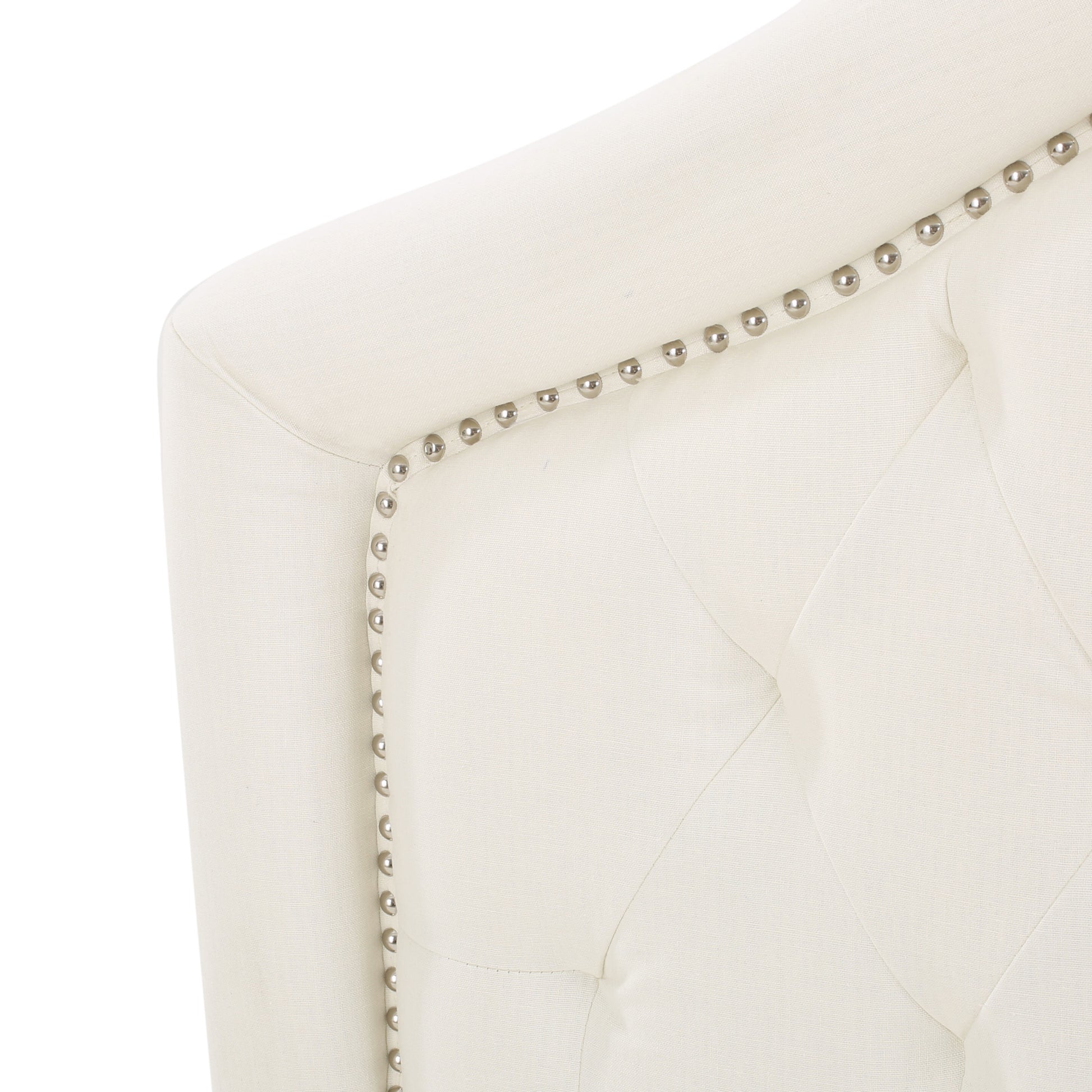 Cream upholstered armchair detail with tufted design and polished nailhead trim