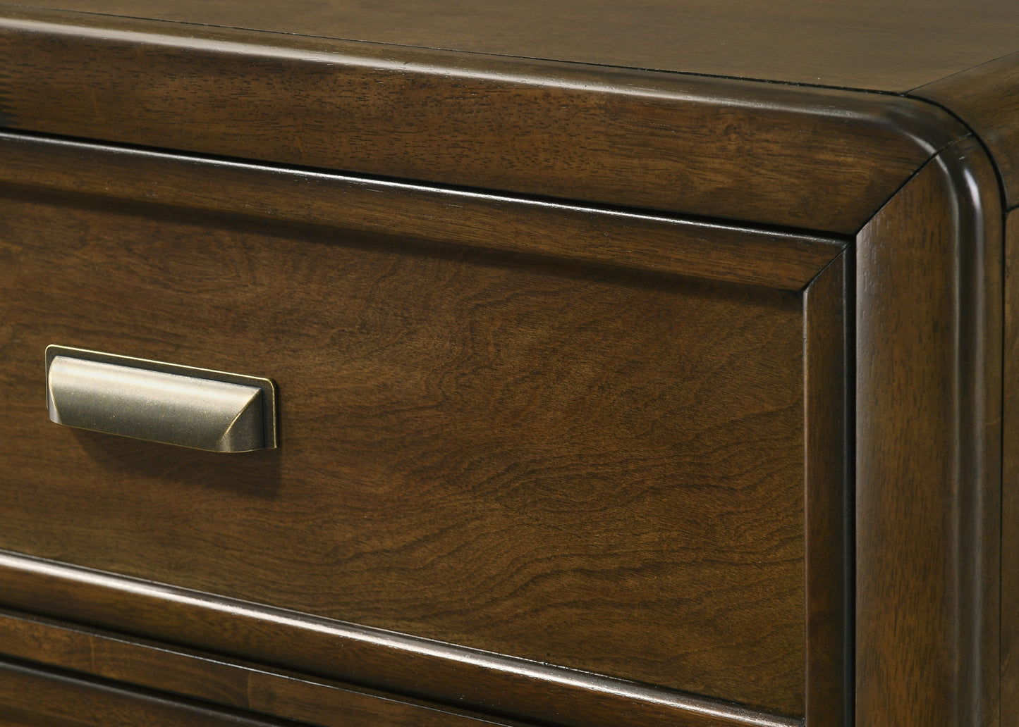Antique brass drawer pull on a dark wood dresser with visible grain