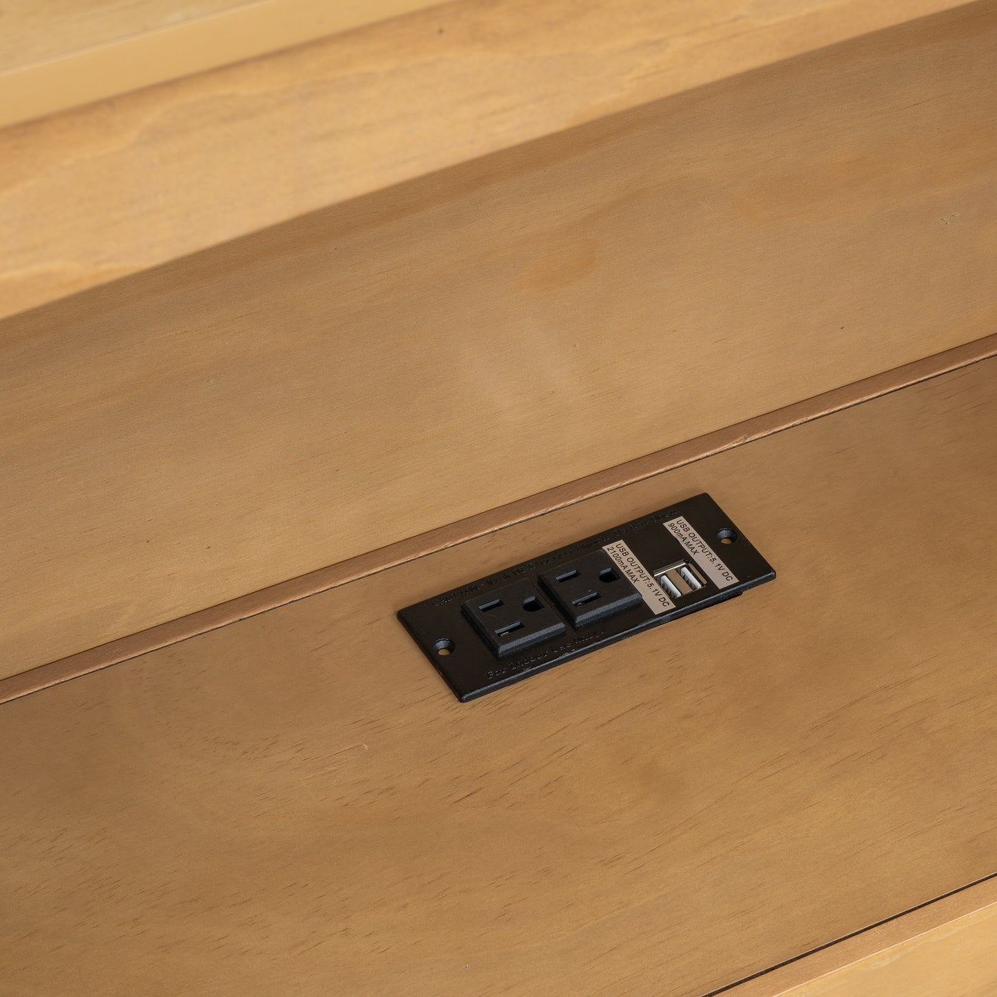 Black power outlet with two USB ports on a wood surface
