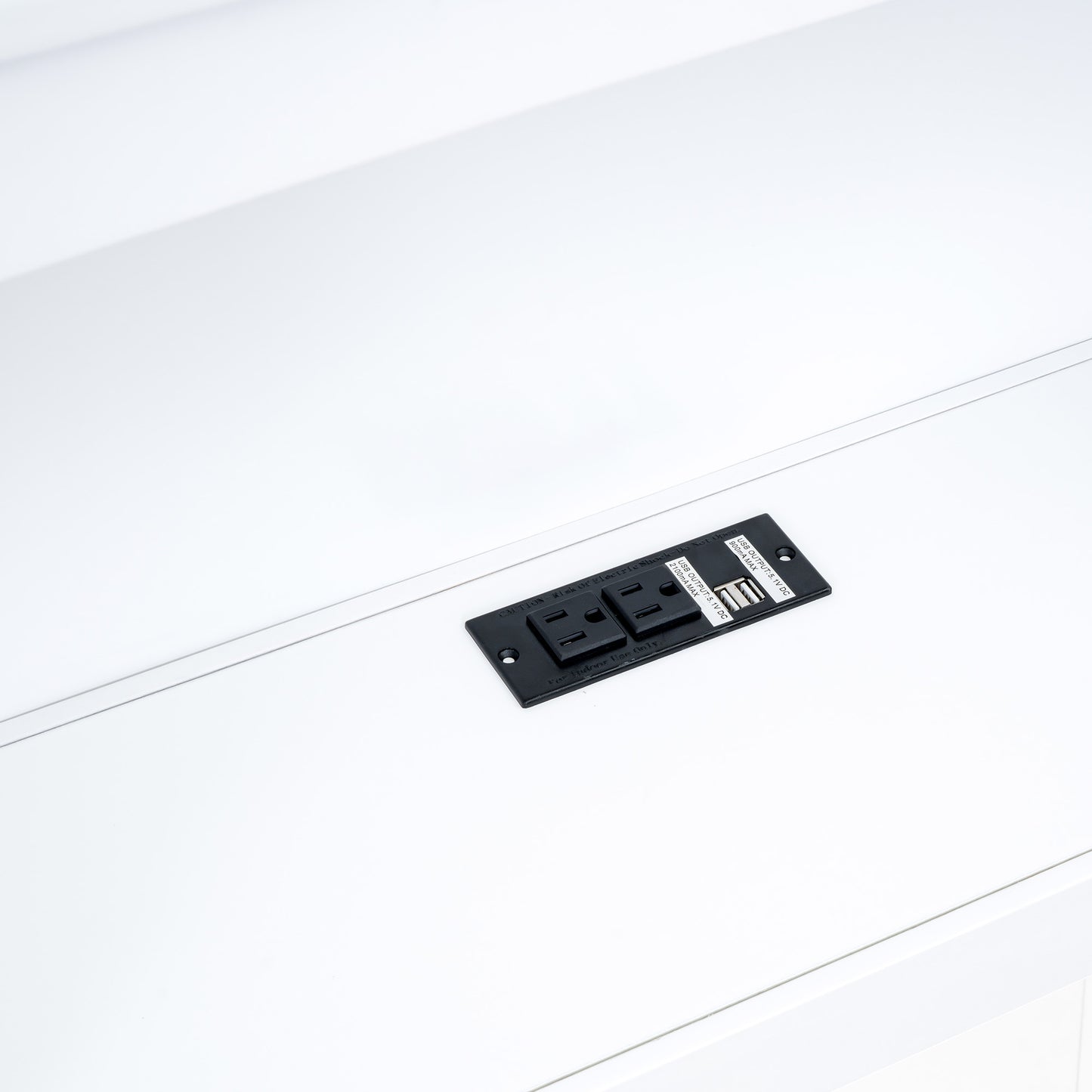 Black recessed power outlet with two AC sockets and two USB ports on white surface