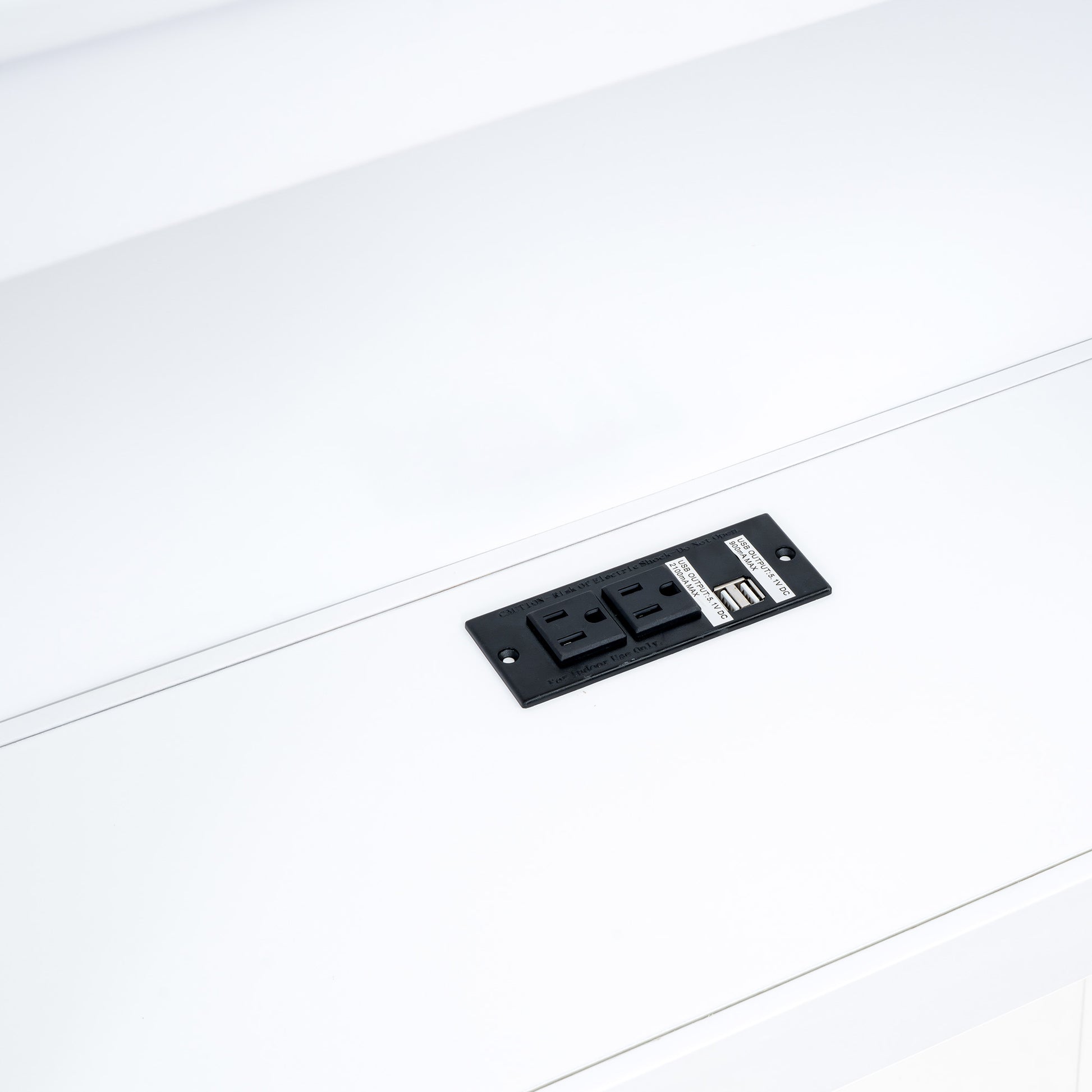 Black recessed power outlet with two AC sockets and two USB ports on white surface