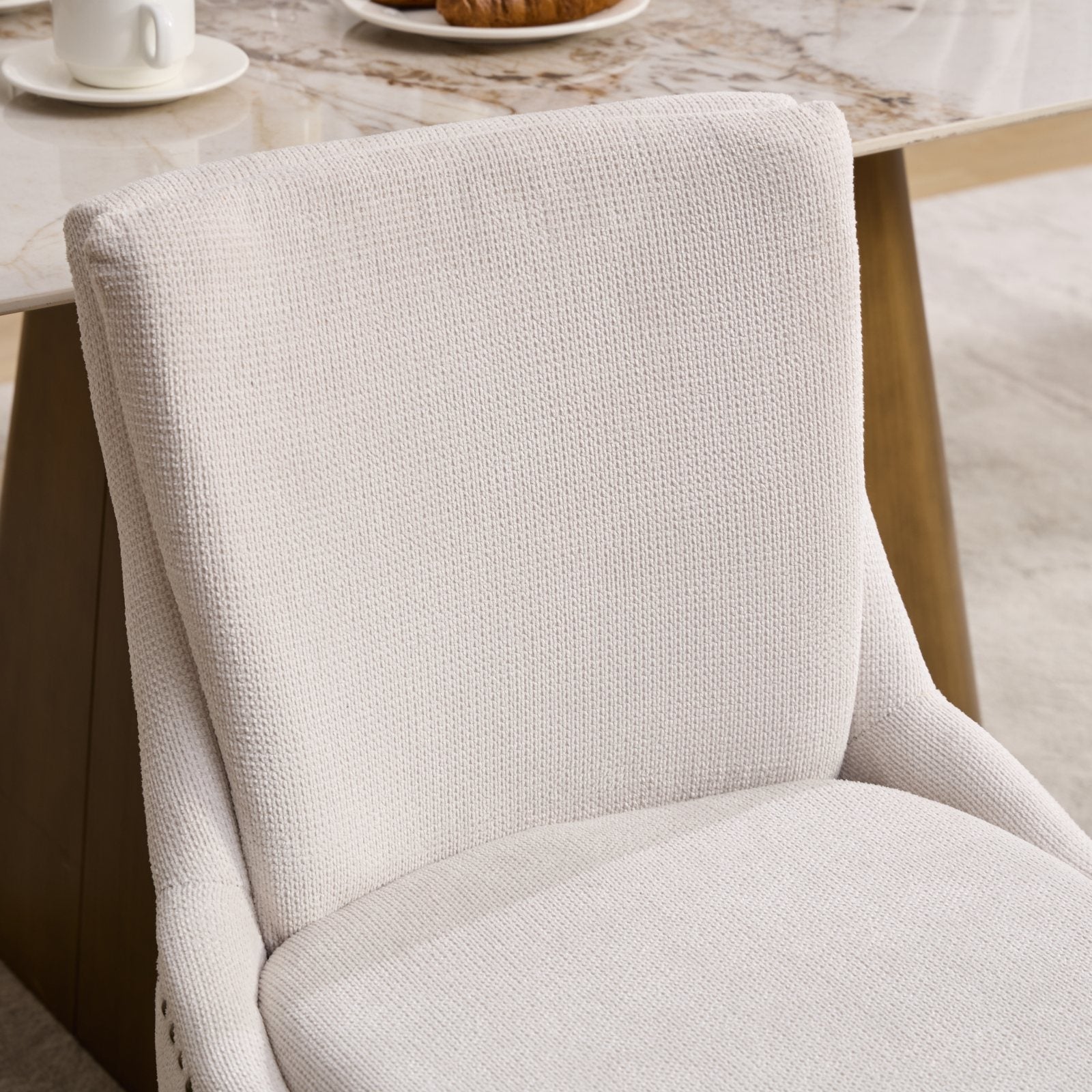 Cream upholstered dining chair with textured fabric and subtle piping detail