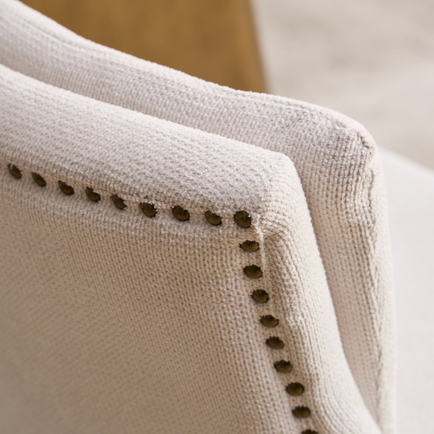 Cream upholstered accent chair with brass nailhead trim