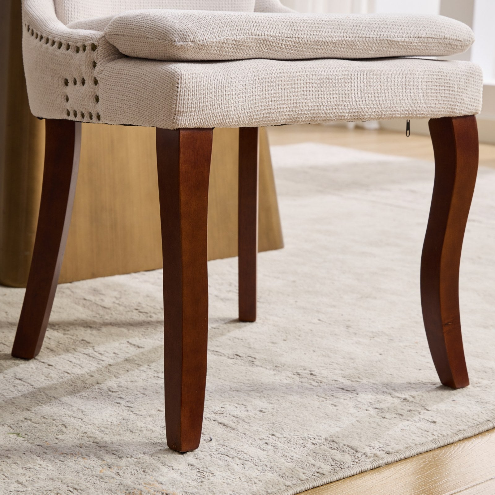Cream upholstered armchair with nailhead trim and dark wood legs
