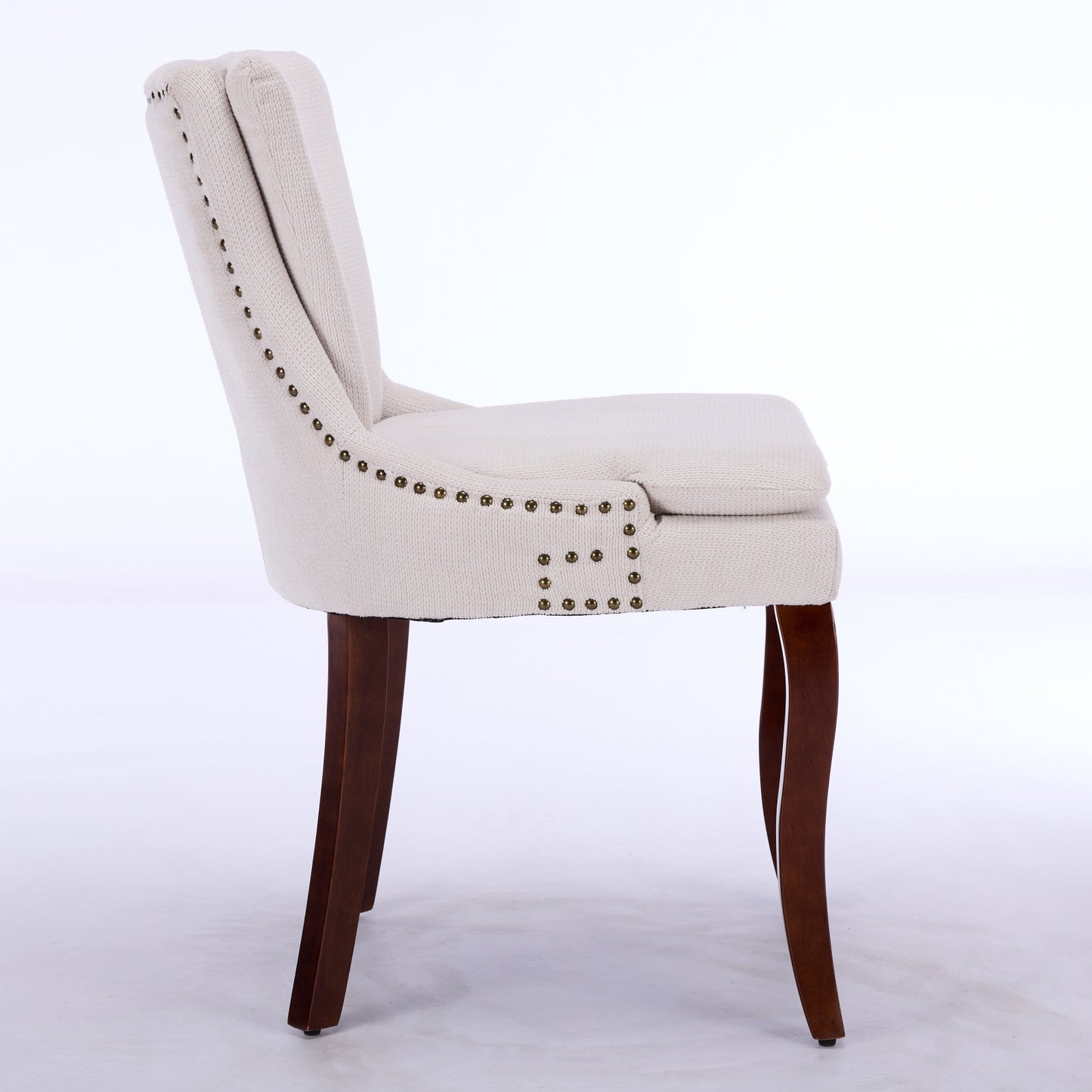 Cream upholstered dining chair with brass nailhead trim and dark wood legs