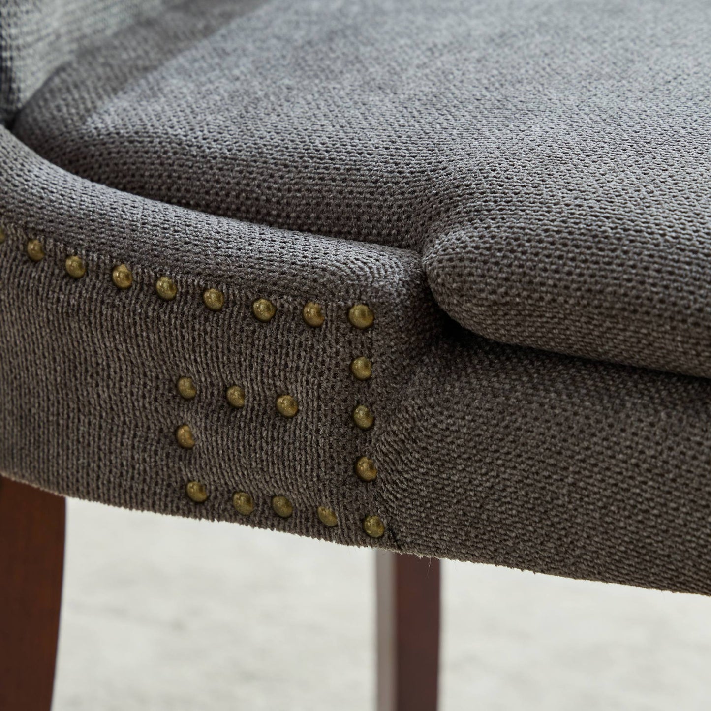 Dark gray upholstered chair detail with brass nailhead trim