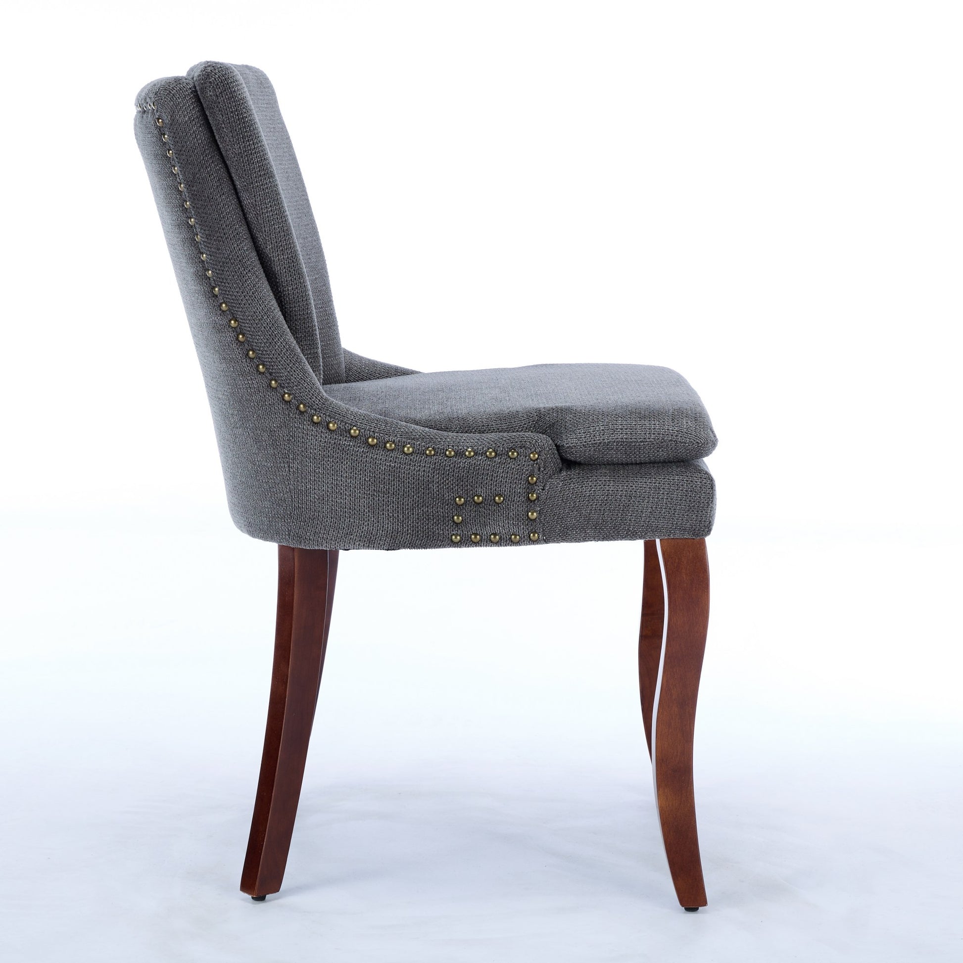 Gray upholstered dining chair with brass nailhead trim and carved wooden legs