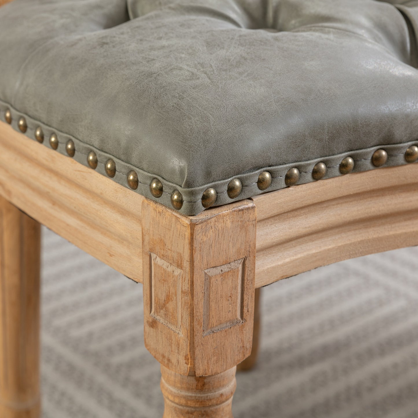 Tufted grey faux leather stool seat with brass nailhead trim and carved wood legs