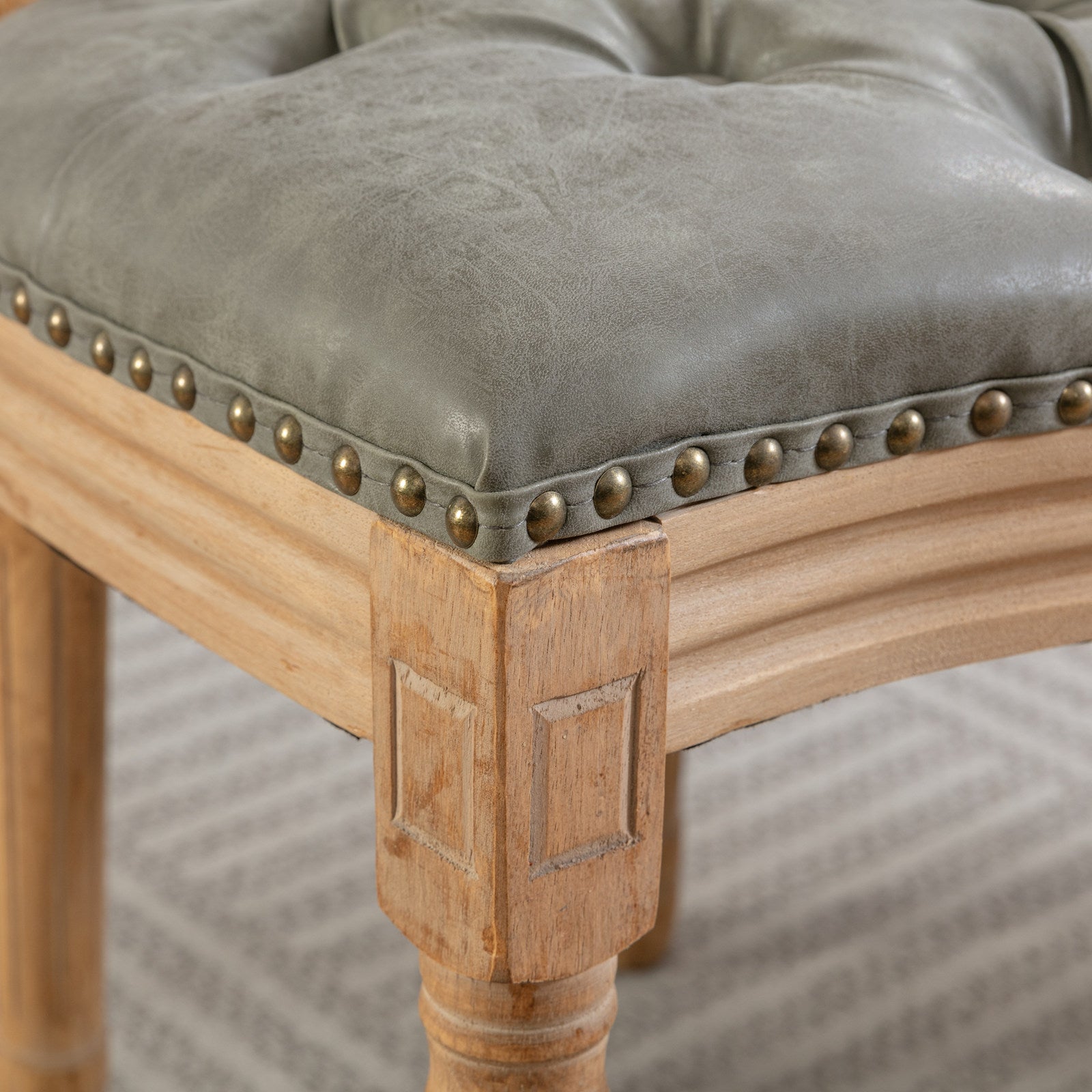 Tufted grey faux leather stool seat with brass nailhead trim and carved wood legs